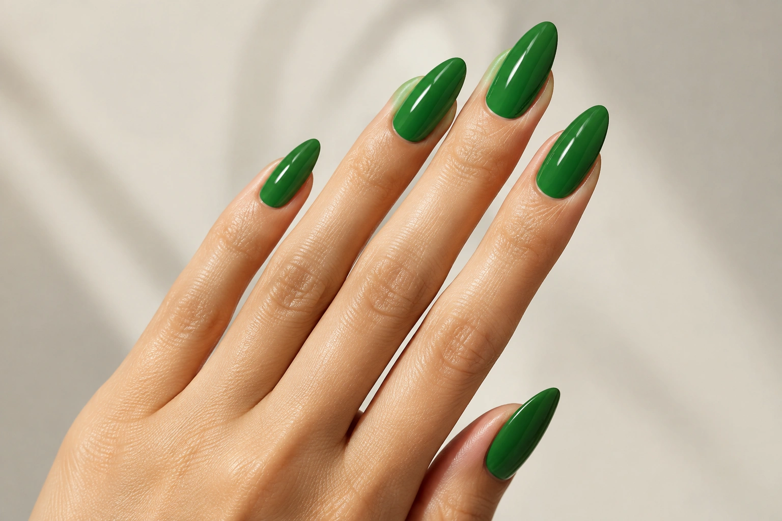 Long almond nails painted in glossy green polish
